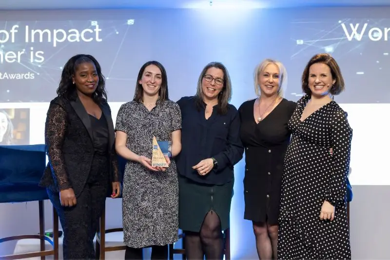 Five women at an awards event, one holding a trophy