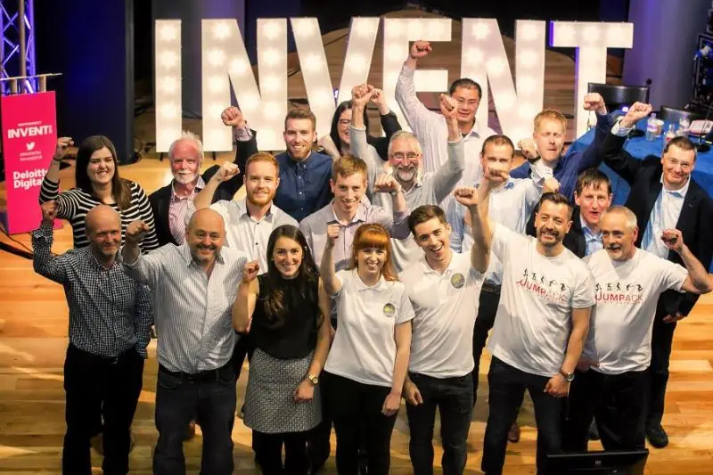 A large group celebrating in front of giant INVENT letters