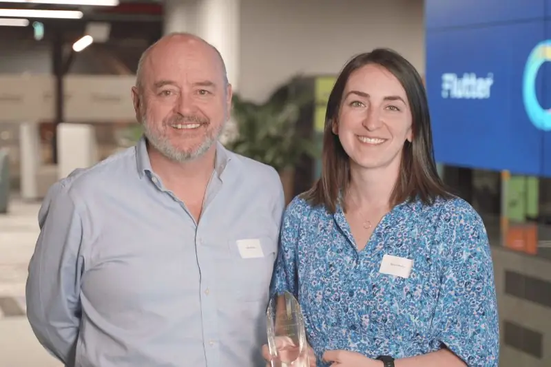 Two people at an event, one holding a glass award