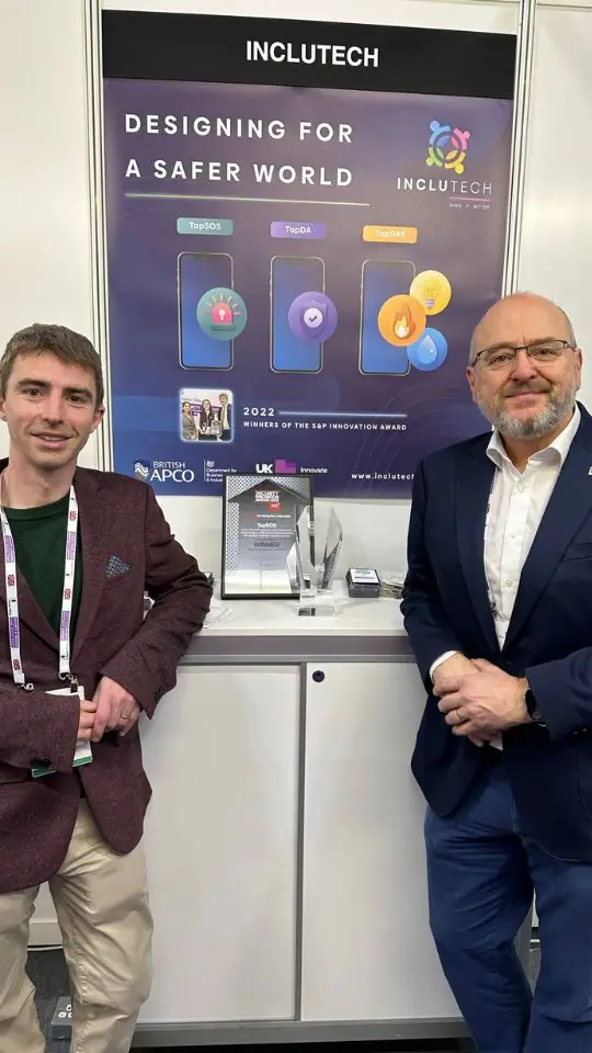 Two people beside the Inclutech Designing for a safer world exhibition stand