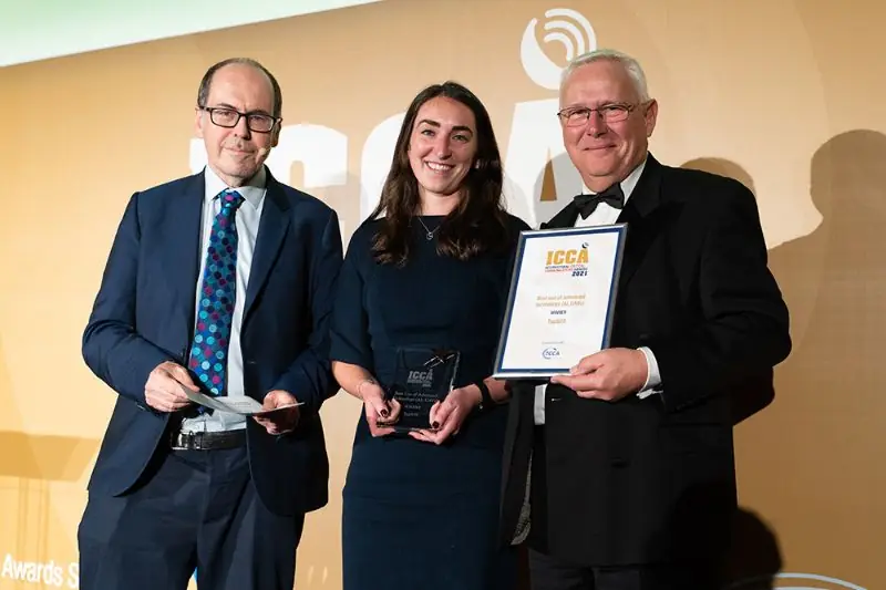 Three people holding an ICCA award trophy and certificate